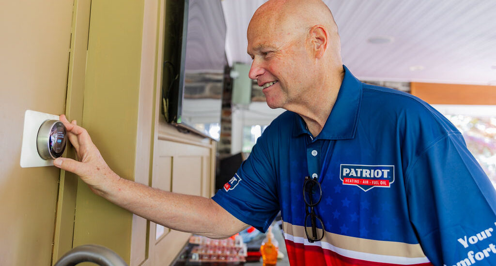 Patriot Heating, Air and Fuel Oil service worker adjusting a smart thermostat for better indoor air quality in Bristol, PA