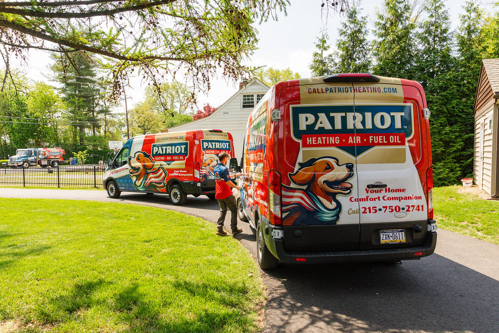 Patriot Heating, Air and Fuel Oil service trucks parked outside a Levittown, PA home for HVAC service
