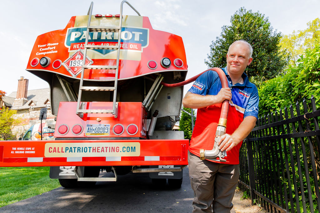a technician from Patriot Heating, Air and Fuel Oil pulls the hose from a branded vehicle as he makes a heating oil delivery in Doylestown, PA