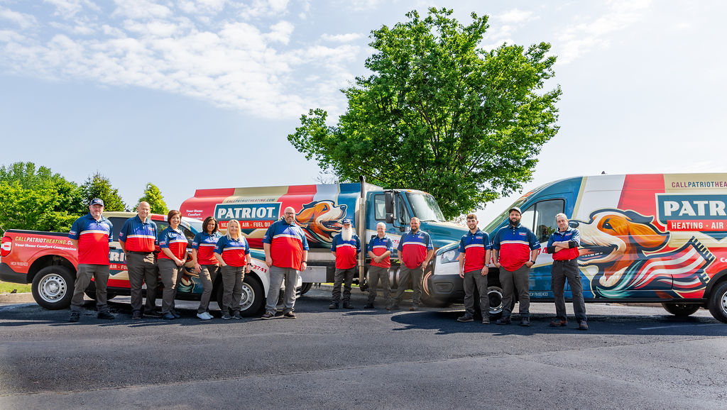the AC services team from Patriot Heating, Air and Fuel Oil poses in front of branded vehicles in Levittown, PA