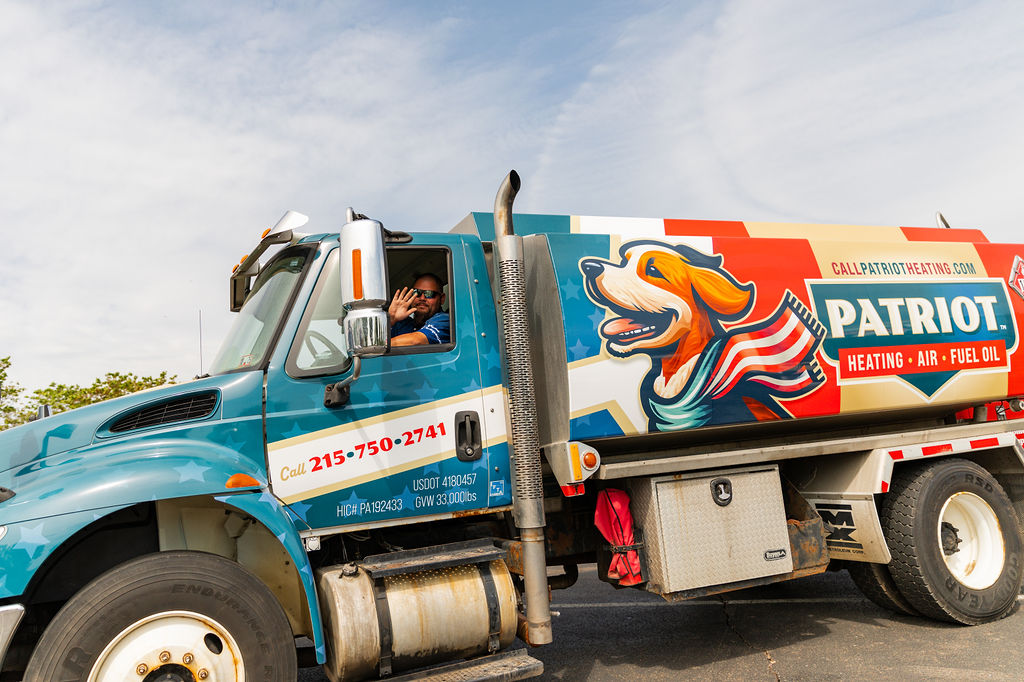 a driver from Patriot Heating, Air and Fuel Oil waves hello from a branded vehicle as he prepares for heating oil delivery in Levittown, PA